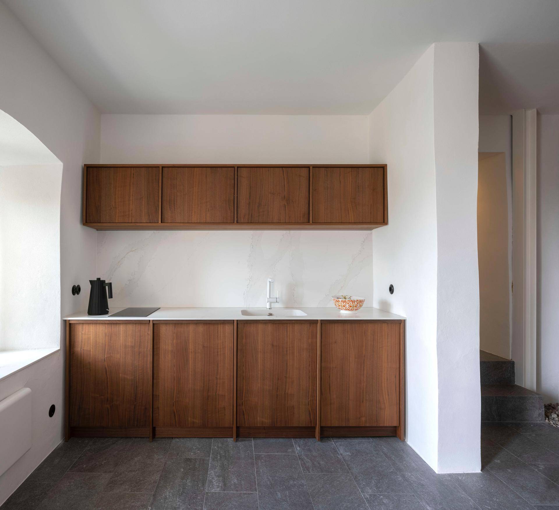 Moderne Küchenzeile mit Holzfronten, weißer Arbeitsplatte und integriertem Spülbecken.