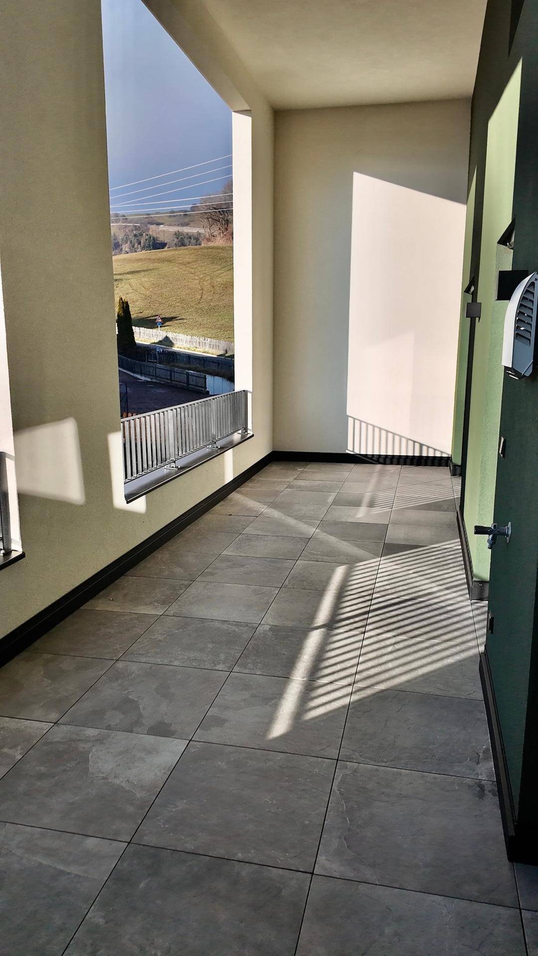 Lange, geflieste Terrasse mit Blick auf die umliegende Landschaft und viel Sonnenlicht.