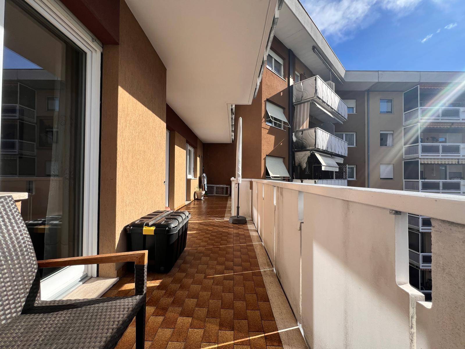 Langer Balkon mit Fliesenboden und Blick auf die umliegenden Wohngebäude.