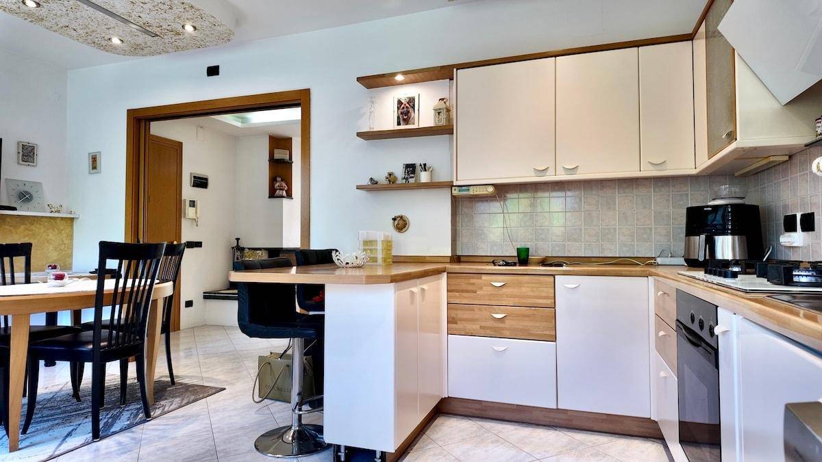 Funktionale Küche mit weißen Schränken, Holztheke und Essbereich.