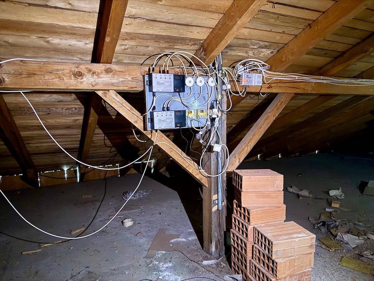 Dachboden mit freiliegenden Holzbalken und elektrischen Installationen, ideal für Lagerzwecke.