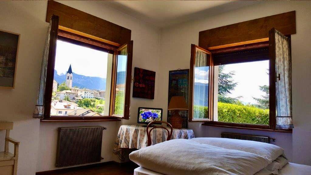 Helles Schlafzimmer mit zwei Fenstern, Blick auf das Dorf und die Landschaft.