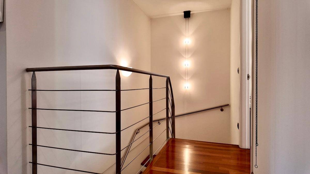 Treppenhaus mit modernem Geländer, Holzboden und indirekter Beleuchtung.