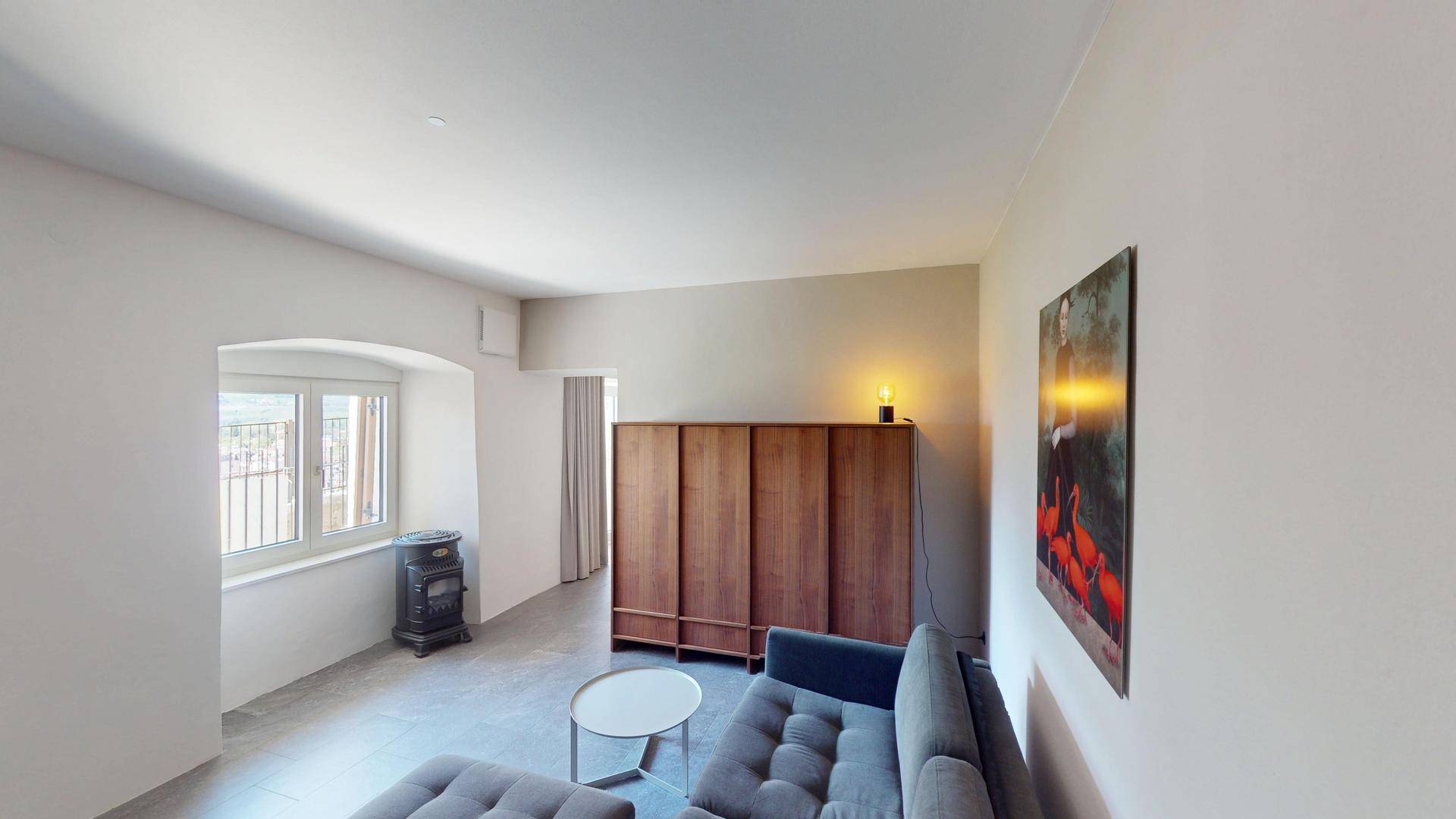 Helles Wohnzimmer mit modernem Sofa, Holzelementen und einem gemütlichen Ofen.