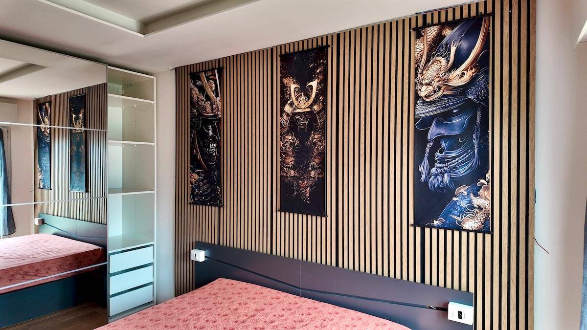 Schlafzimmer mit dekorativer Holzwand, großem Bett und Spiegelschrank.