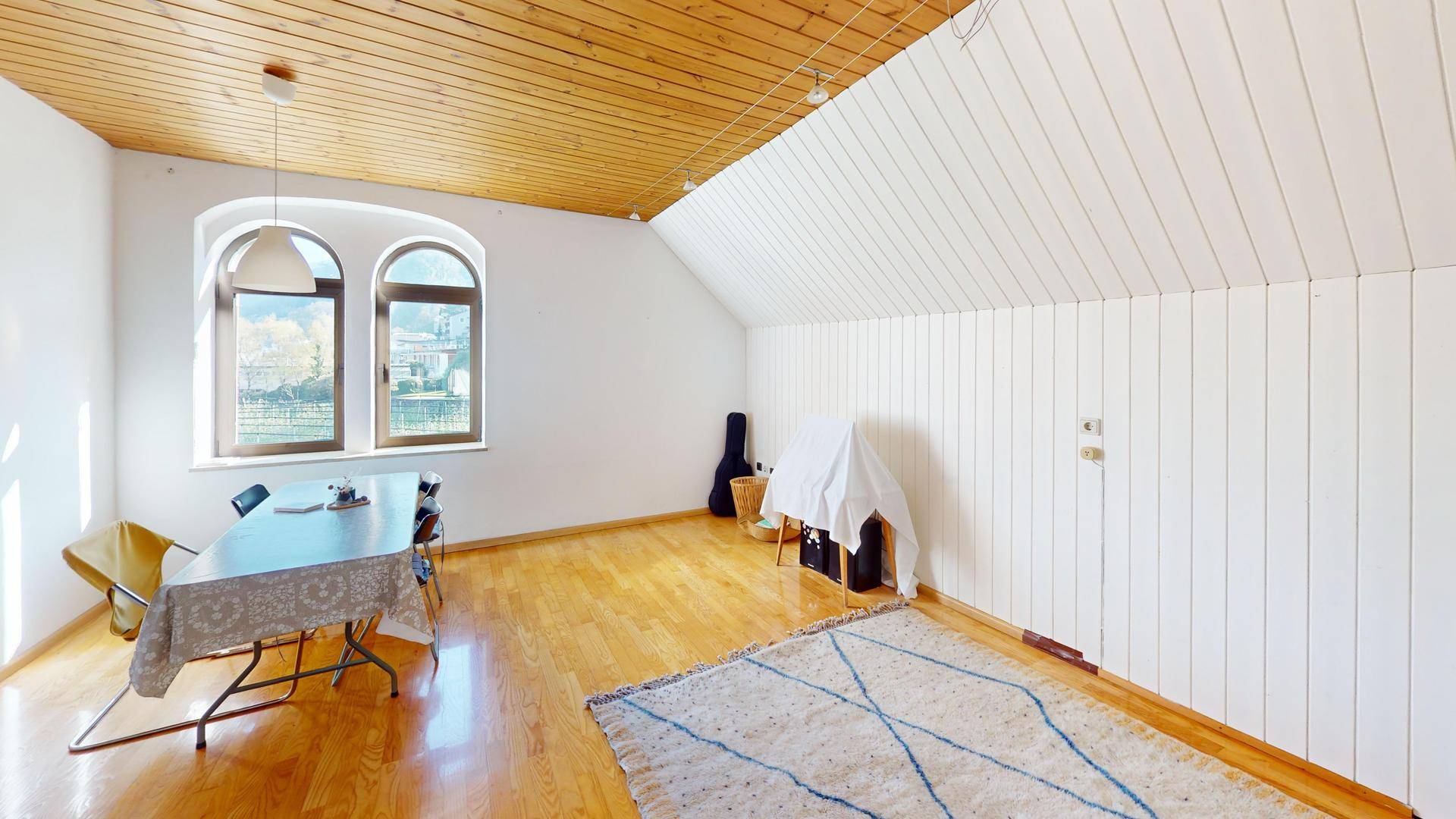 Heller Essbereich mit Holzdielenboden, Dachschräge und Rundbogenfenstern.