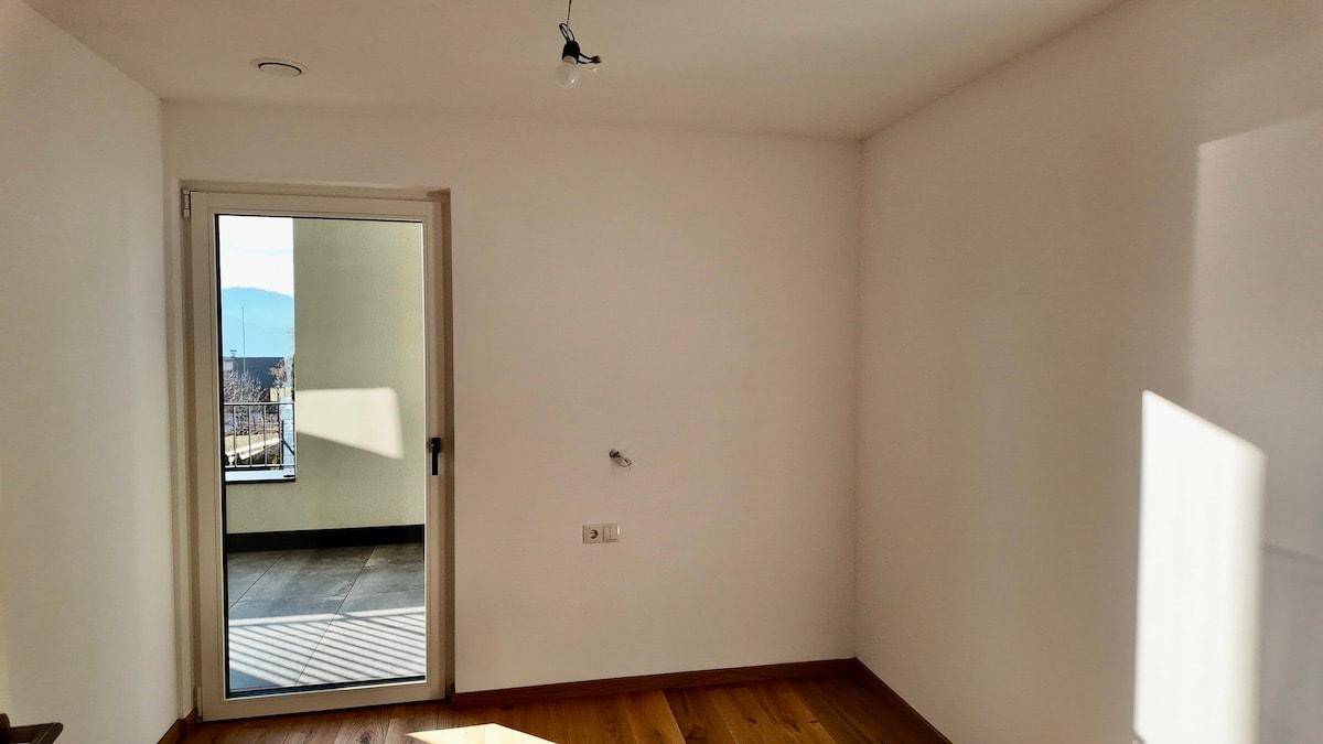 Helles Zimmer mit Holzboden und direktem Zugang zu einem Außenbereich, ideal für Entspannung.
