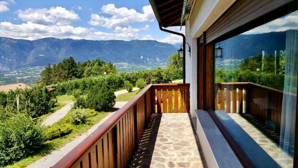 Sonniger Balkon mit Holzboden und atemberaubendem Panoramablick auf die Berge.