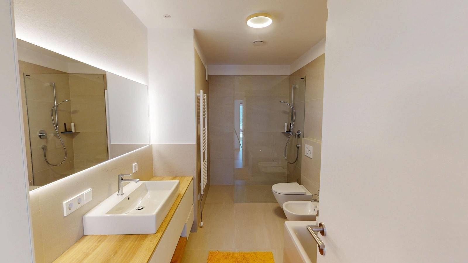 Modernes Badezimmer mit großem Waschtisch, begehbarer Dusche, WC und Bidet.