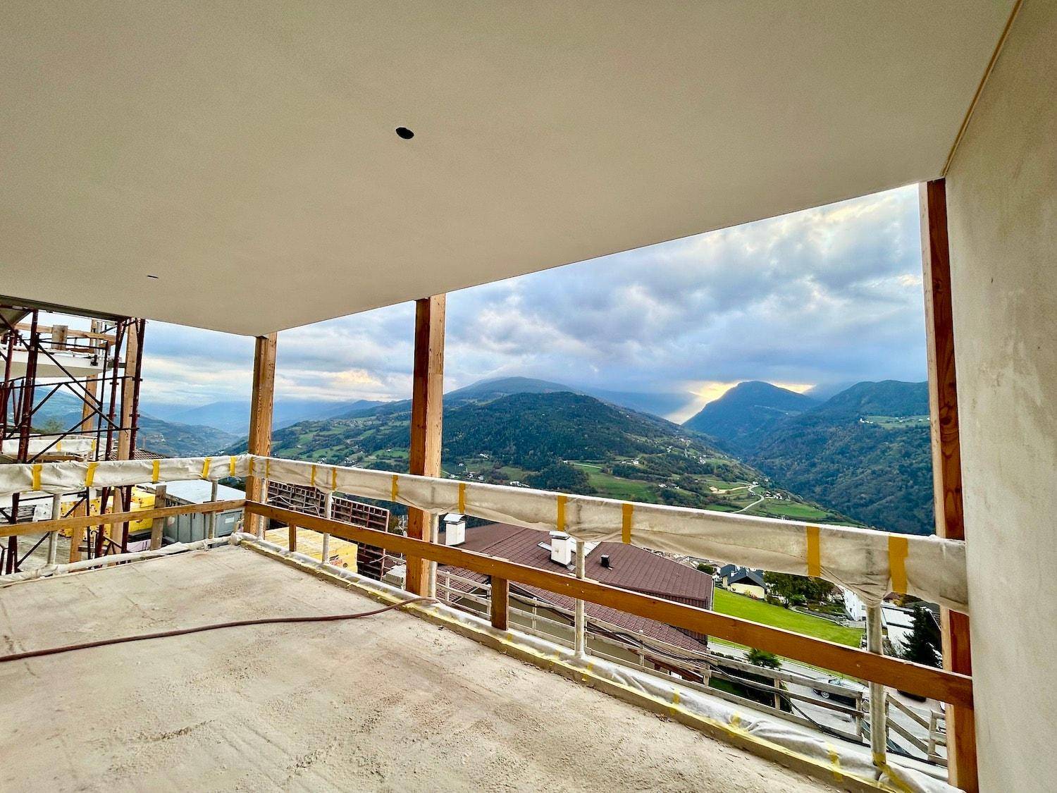 Geräumiger, im Bau befindlicher Balkon mit Betonboden und Holzstützen, bietet weiten Bergblick.