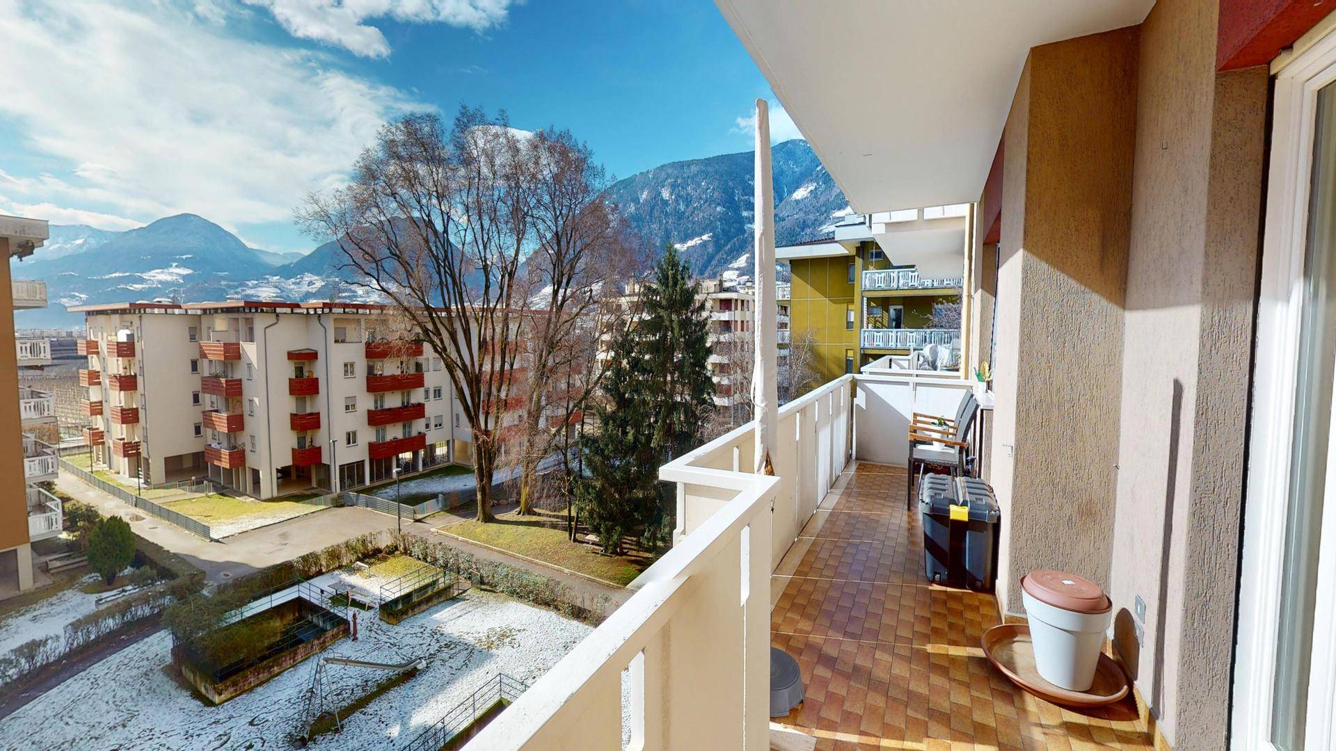 Breiter Balkon mit Fliesenboden und Panoramablick auf die schneebedeckten Berge.