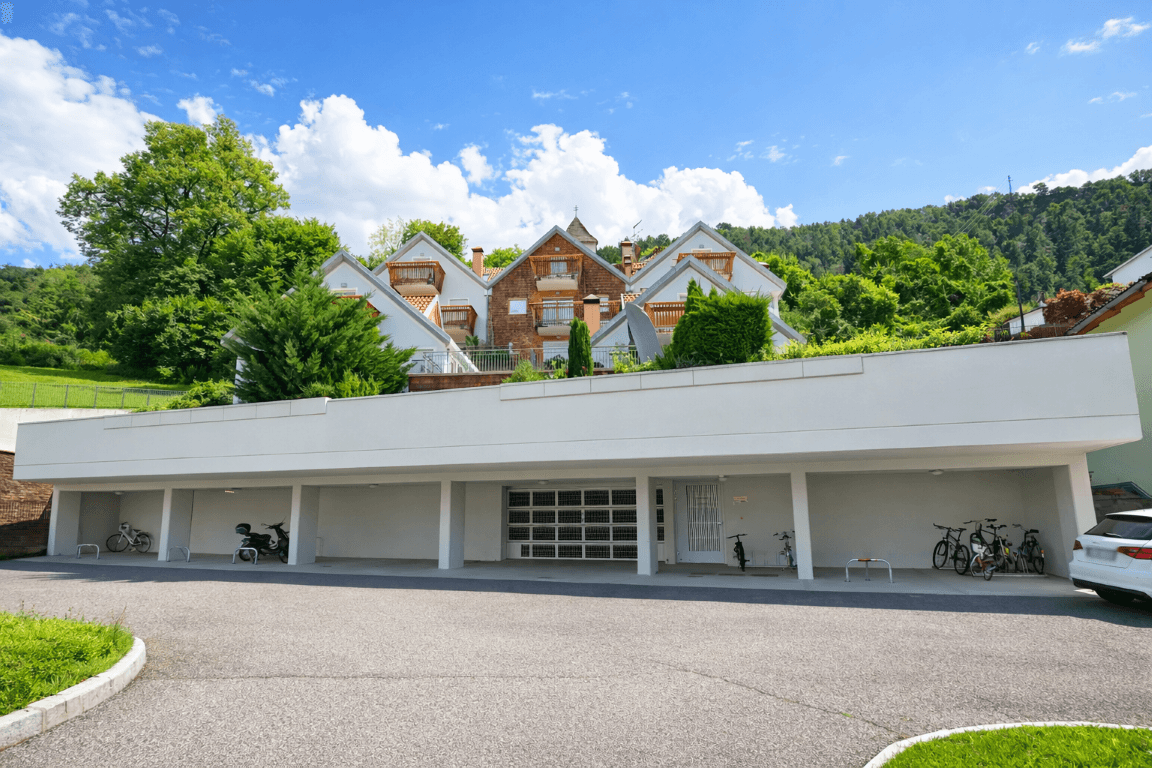 Außenansicht der Wohnanlage mit Tiefgaragenzufahrt und Stellplätzen im Freien.