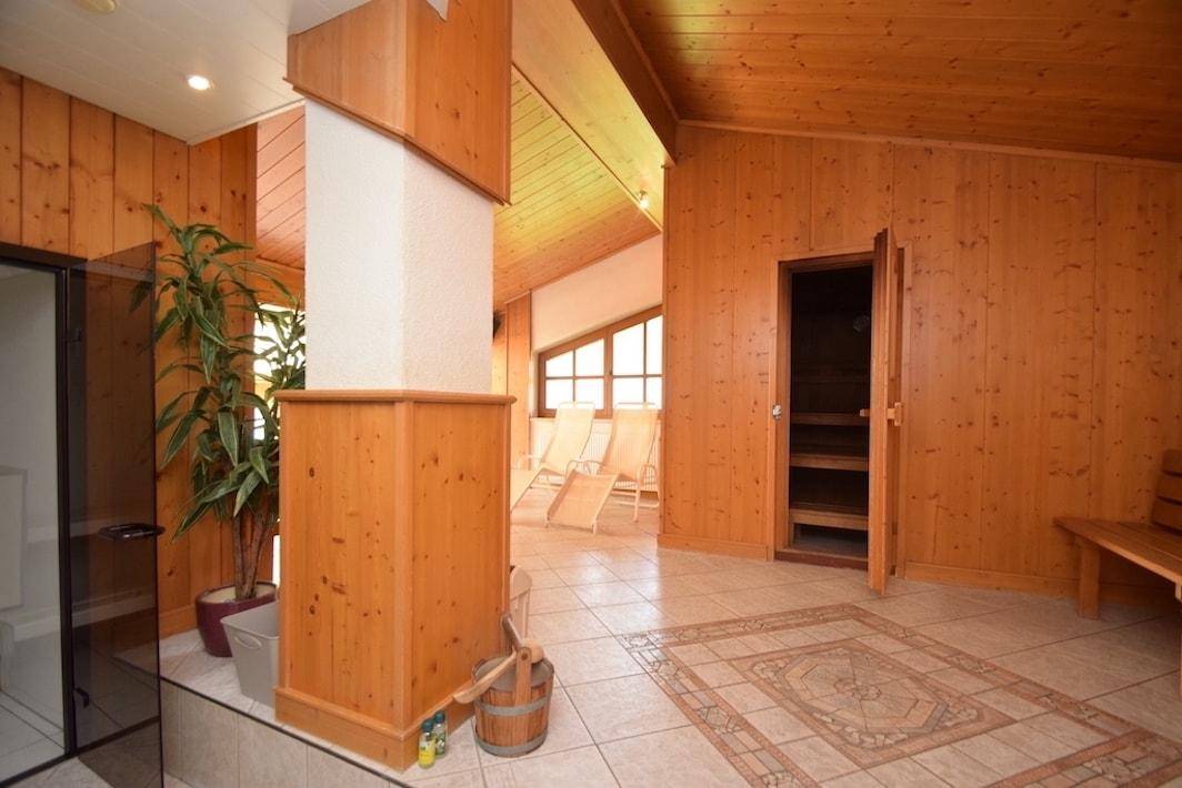 Entspannender Wellnessbereich mit Sauna, Liegestühlen und Holzverkleidung für eine gemütliche Atmosphäre.