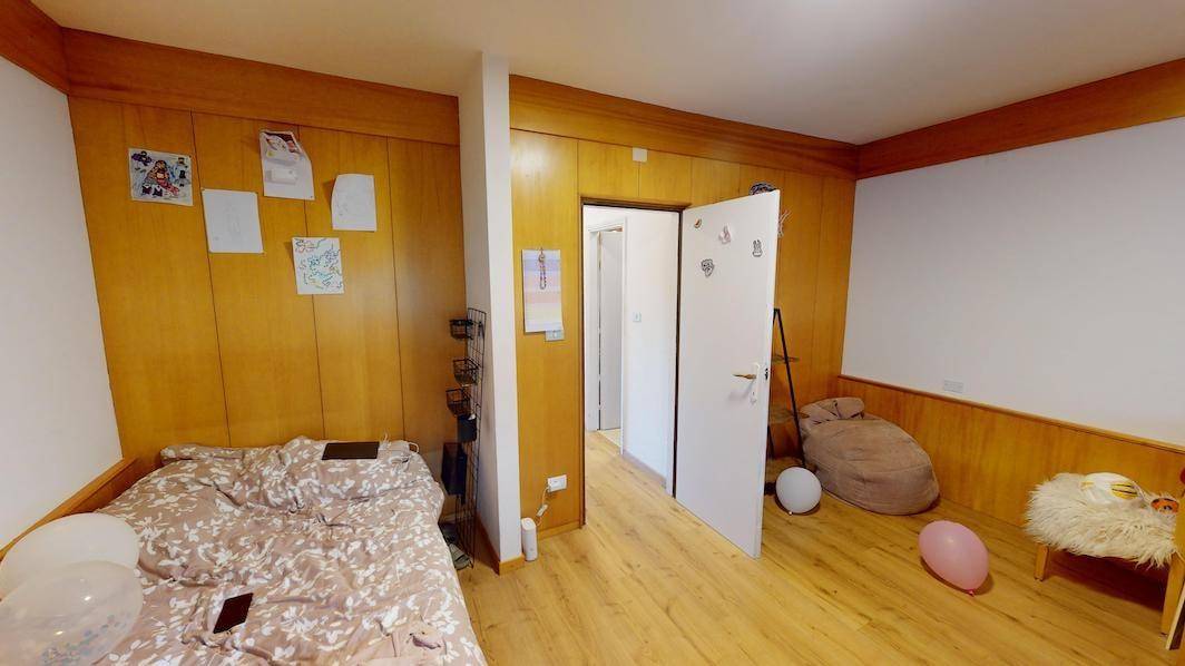 Gemütliches Zimmer mit Holzwänden, Bett und Laminatboden.