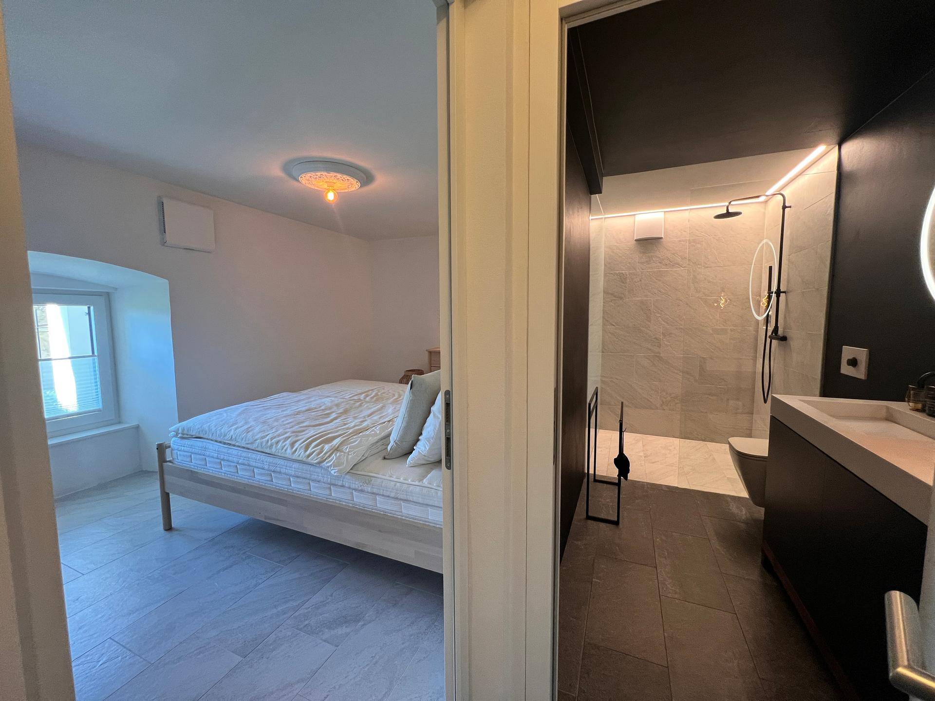 Schlafzimmer mit Blick auf das angrenzende, modern gestaltete Badezimmer.