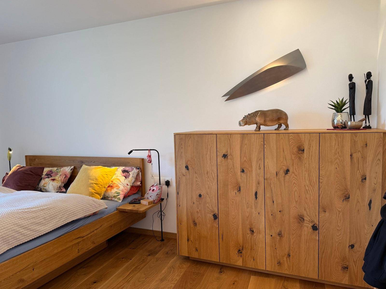 Schlafzimmer mit Holzbett, passendem Schrank und stilvoller Wandbeleuchtung.