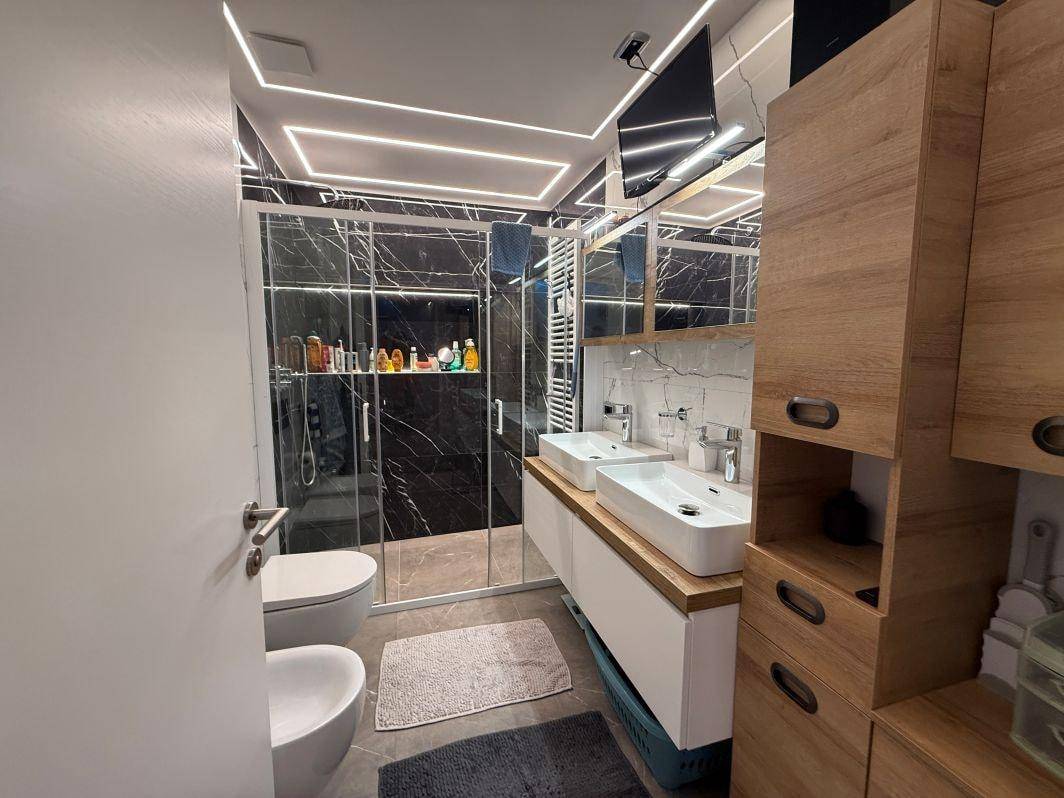 Modernes Badezimmer mit Doppelwaschbecken, Bidet und großer Duschkabine.