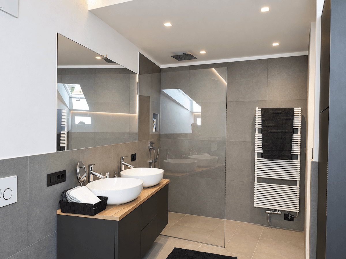 Helles Badezimmer mit Doppelwaschbecken, begehbarer Dusche und beheiztem Handtuchhalter.
