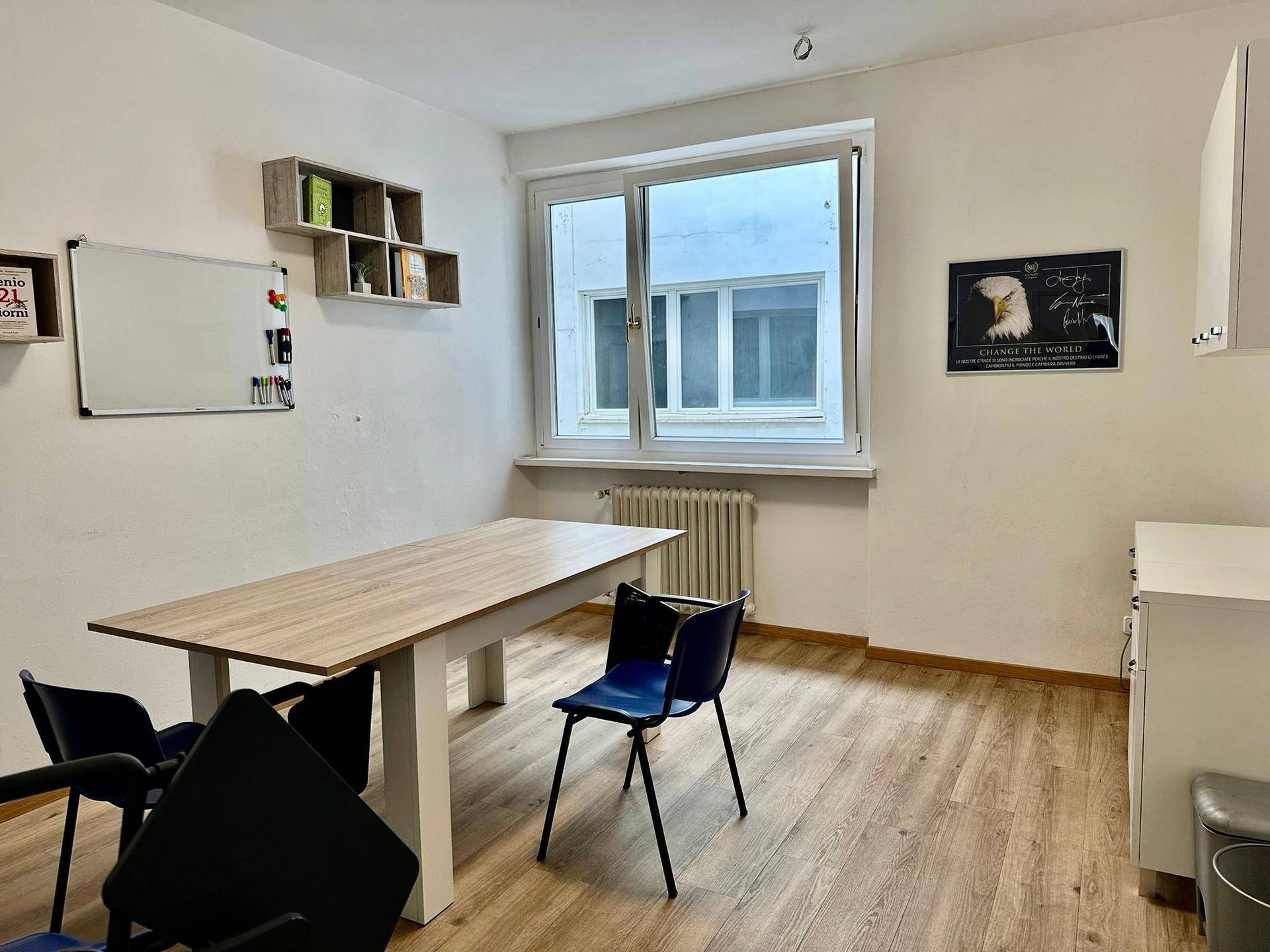 Funktionaler Büroraum mit großem Tisch, Stühlen und Whiteboard für Besprechungen.