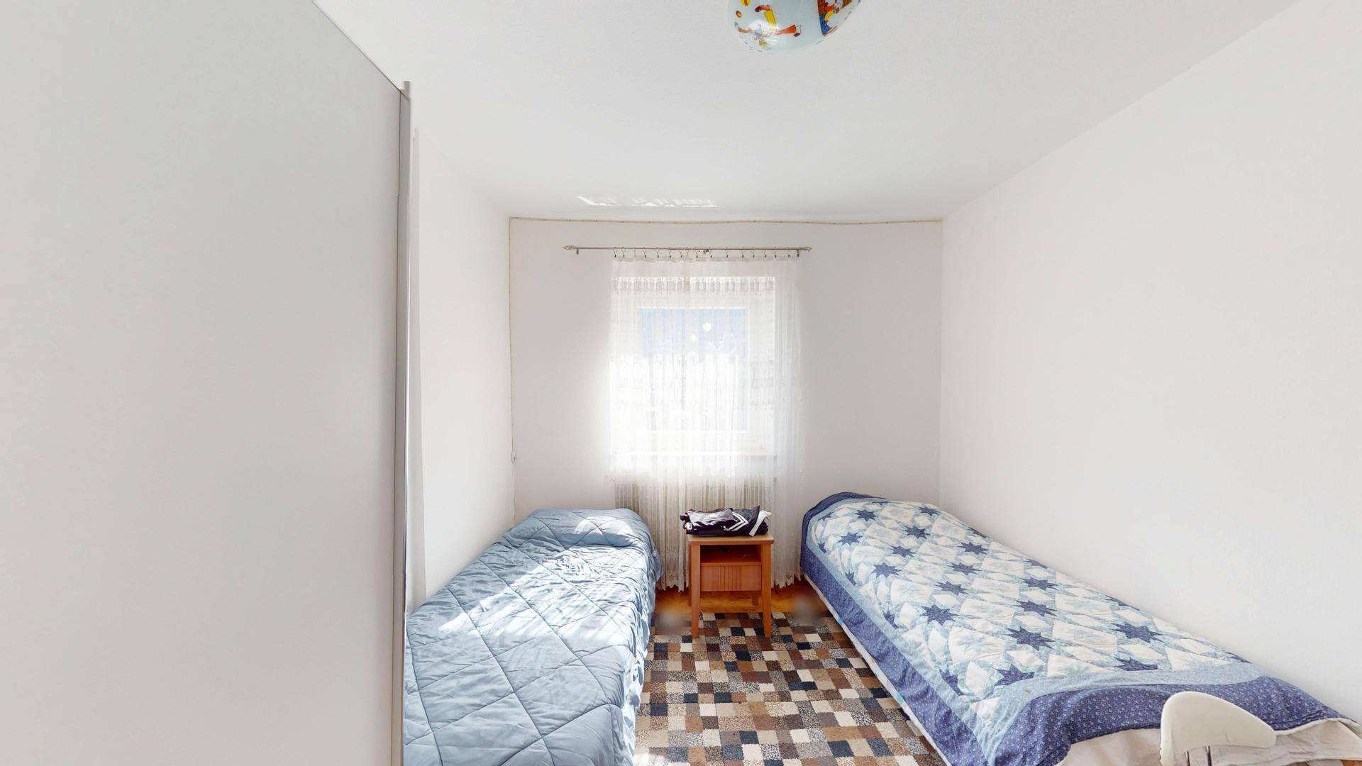 Helles Schlafzimmer mit zwei Einzelbetten, einem kleinen Nachttisch und einem Fenster.