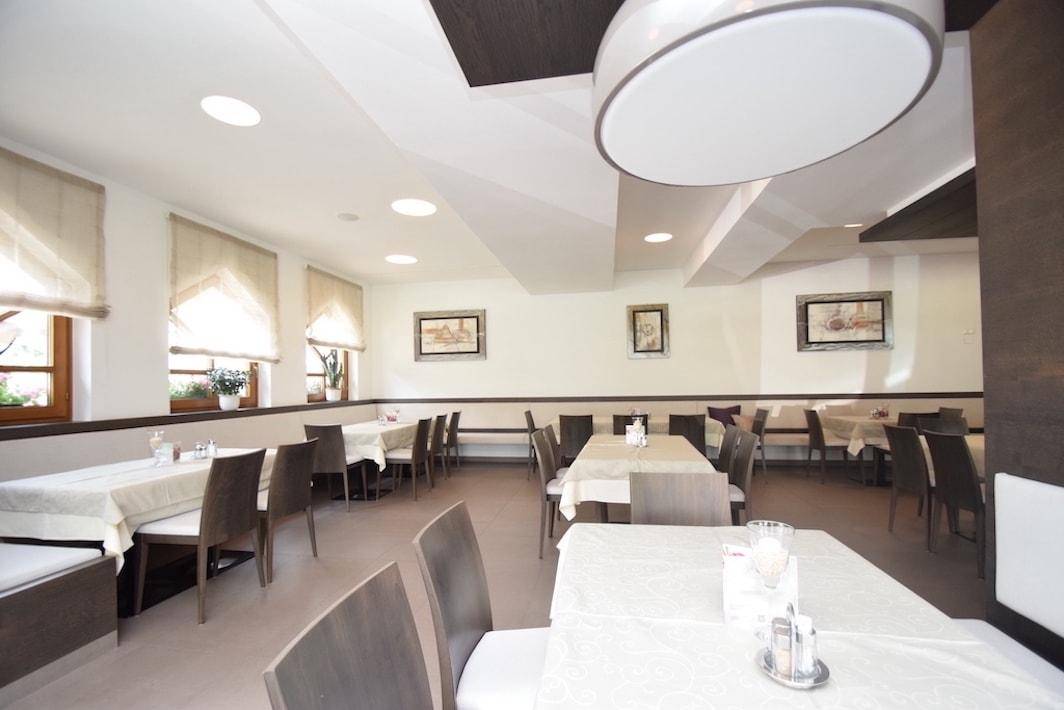 Gemütlicher Speisesaal mit elegant gedeckten Tischen, bequemen Stühlen und dekorativen Bildern an den Wänden.