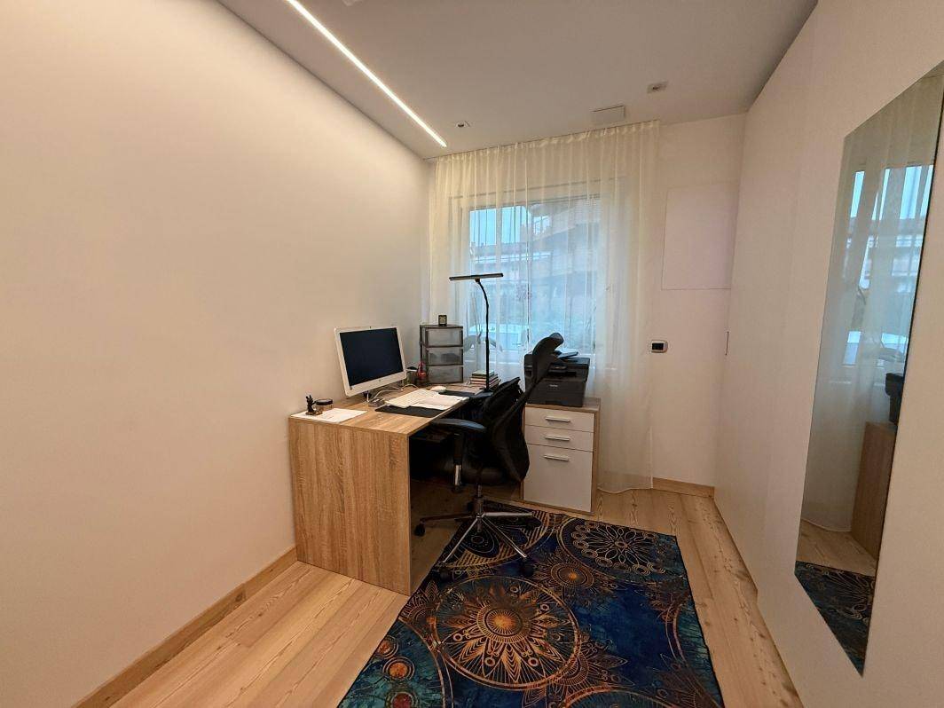 Funktionales Heimbüro mit Schreibtisch, Bürostuhl und großem Fenster für Tageslicht.