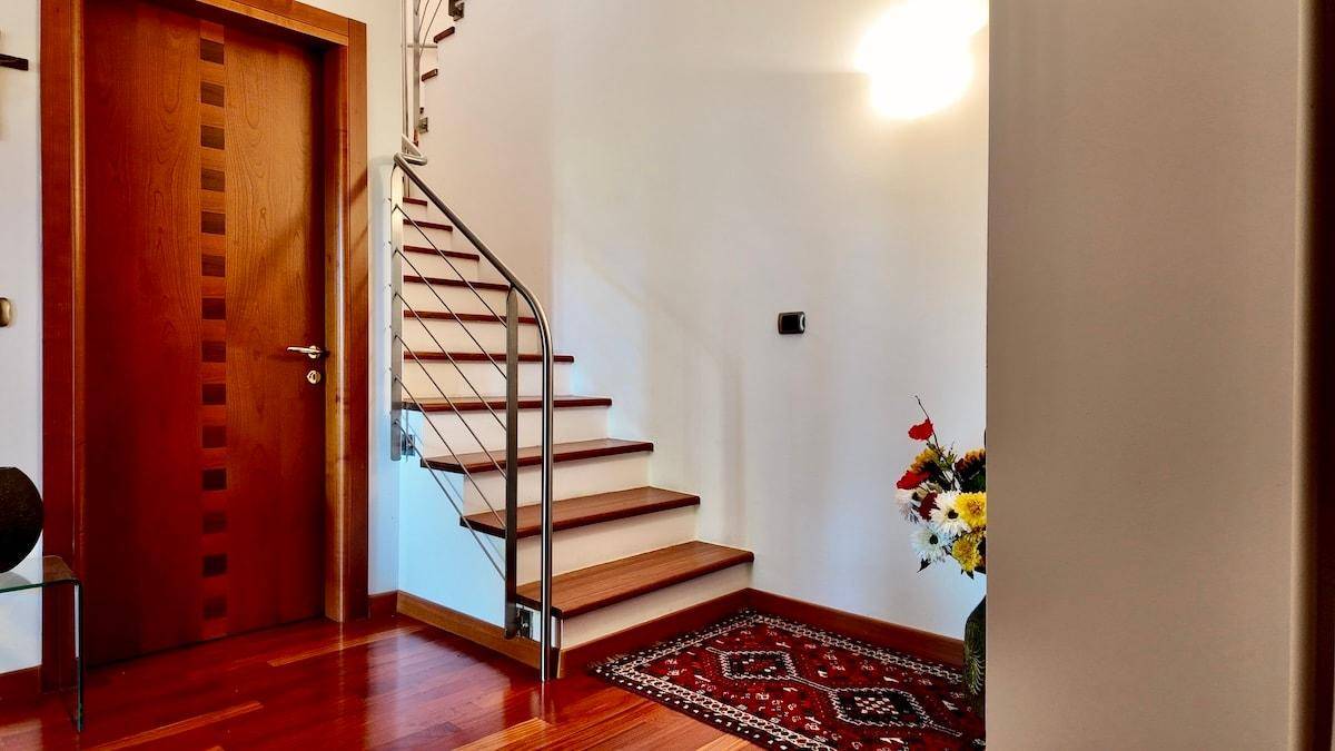 Heller Eingangsbereich mit Holzboden, moderner Treppe und Holztür.
