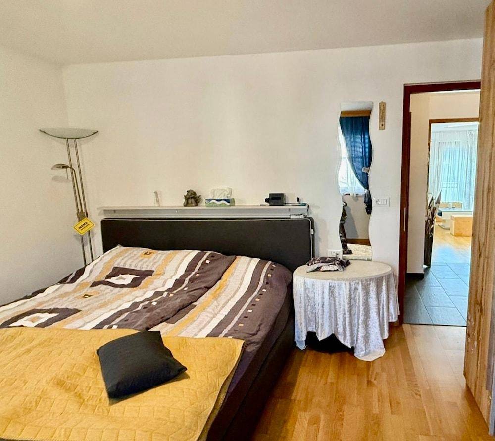Schlafzimmer mit Doppelbett, Parkettboden und Zugang zu einem angrenzenden Raum.
