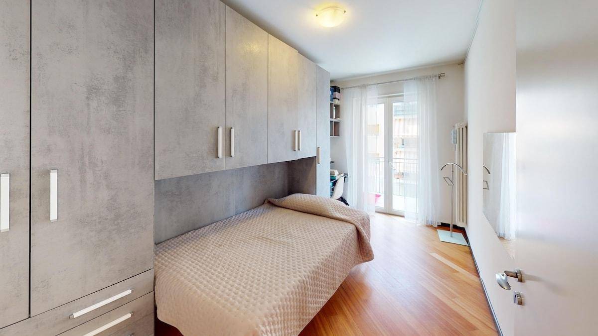 Helles Schlafzimmer mit Einbauschränken, Einzelbett und Balkonzugang.