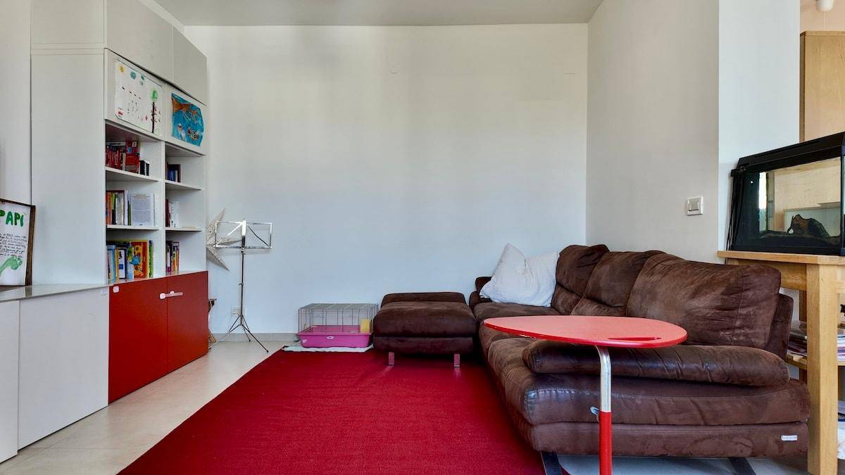 Wohnbereich mit brauner Couch, rotem Teppich und Bücherregal, ideal zum Entspannen.