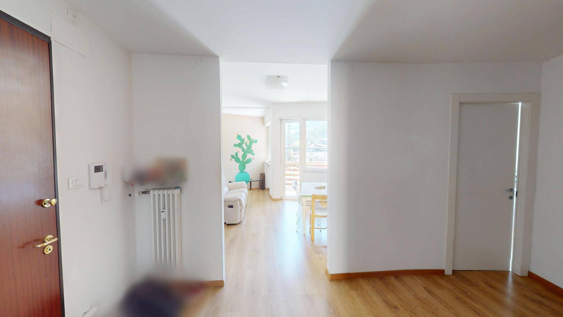 Flur mit Holzboden, der zum hellen Wohnbereich des Apartments führt.