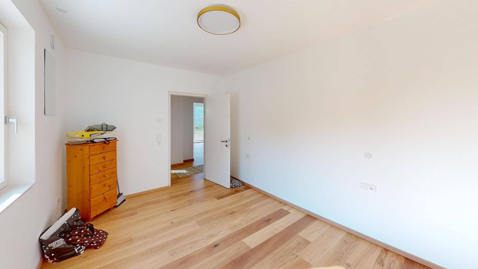 Leeres Zimmer mit Holzboden und einer kleinen Kommode, bereit zur individuellen Gestaltung.