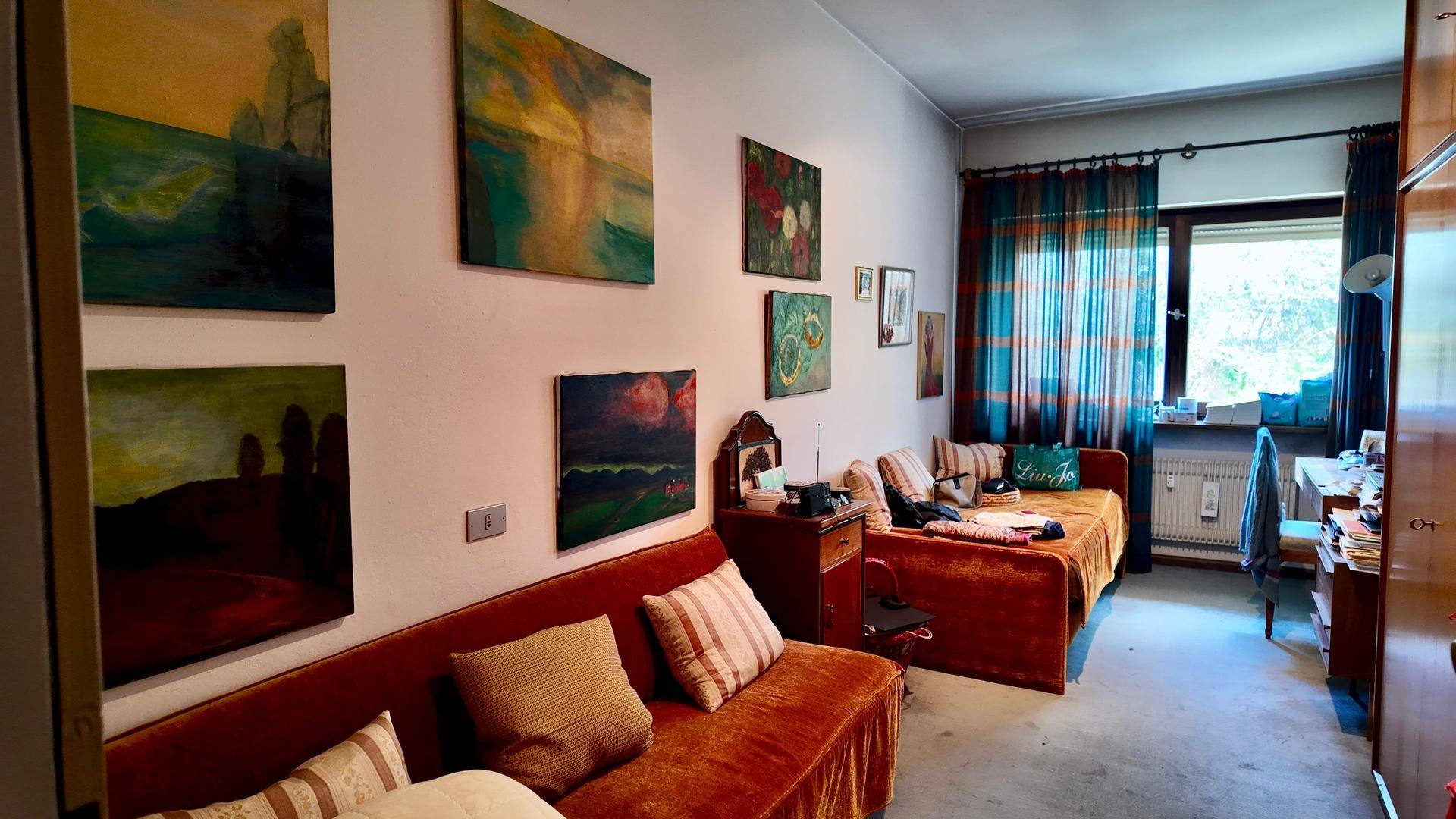Gemütliches Zimmer mit zwei Schlafsofas, Teppichboden und farbenfrohen Bildern an der Wand.