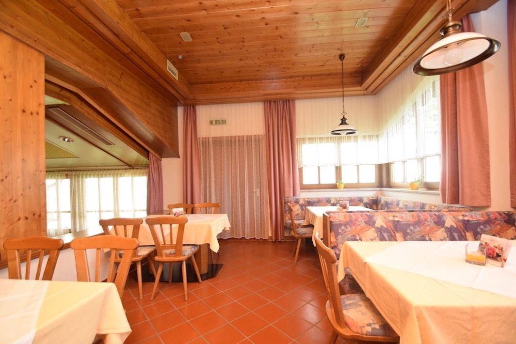 Traditioneller Essbereich mit Holztischen, gepolsterten Bänken und Terrakottafliesen.