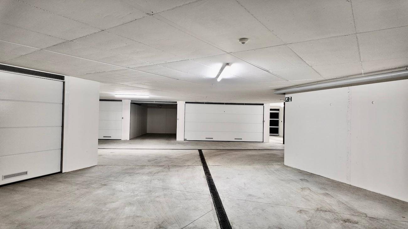 Geräumige Tiefgarage mit mehreren Garagenboxen und Betonboden.