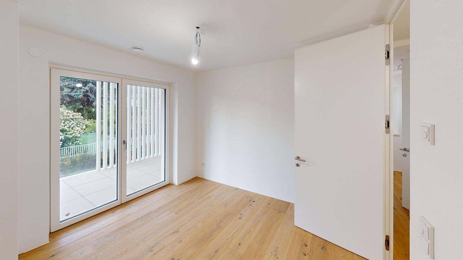 Helles Schlafzimmer mit Holzboden und direktem Zugang zu einem Balkon.