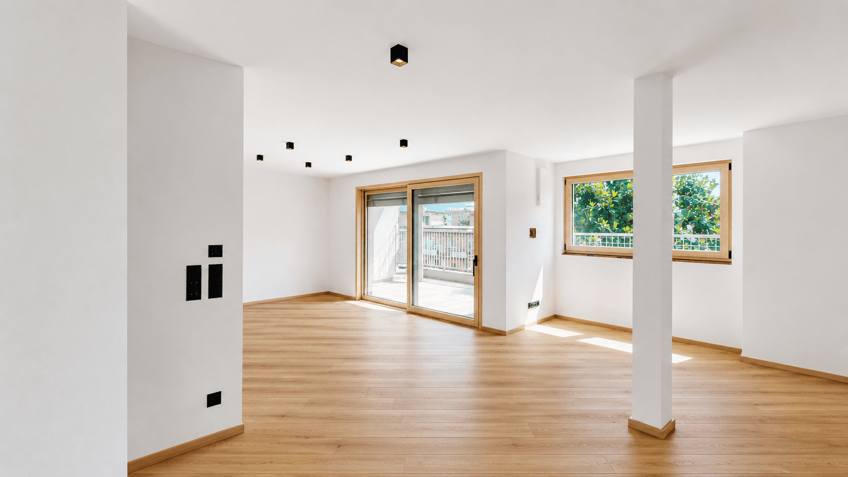 Großzügiger, heller Raum mit Holzboden und Balkonzugang, ideal für offenes Wohnen.