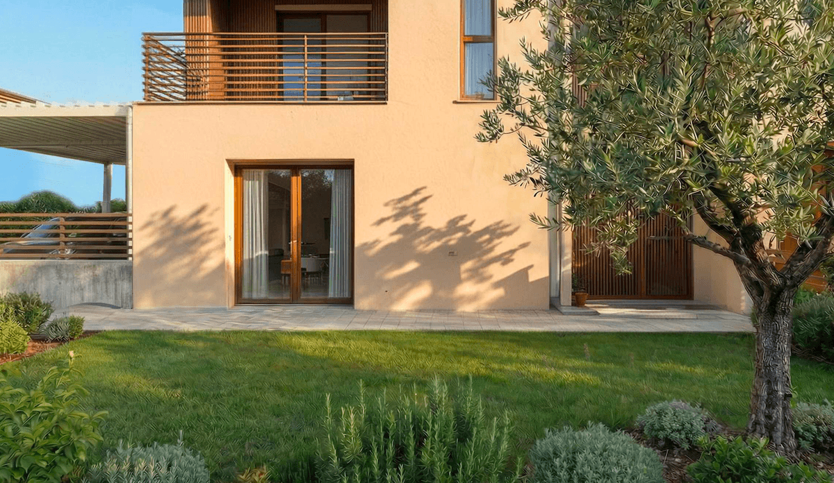 Gepflegter Gartenbereich mit Rasen, mediterranen Pflanzen und einer Terrasse vor dem Haus.