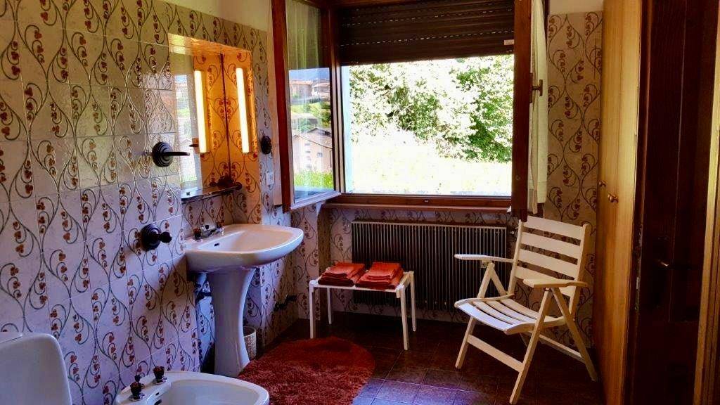 Traditionelles Badezimmer mit gemusterten Fliesen, Waschbecken und Fenster.
