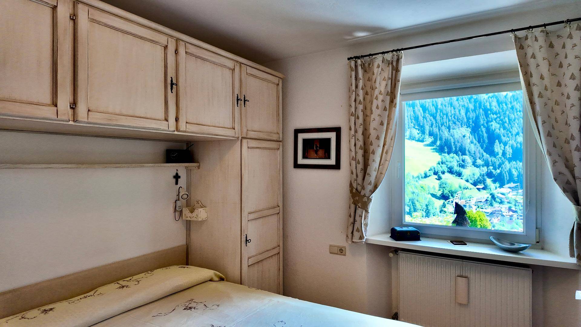 Schlafzimmer mit eingebauten Schränken und einem Fenster, das einen schönen Blick auf die grüne Landschaft bietet.