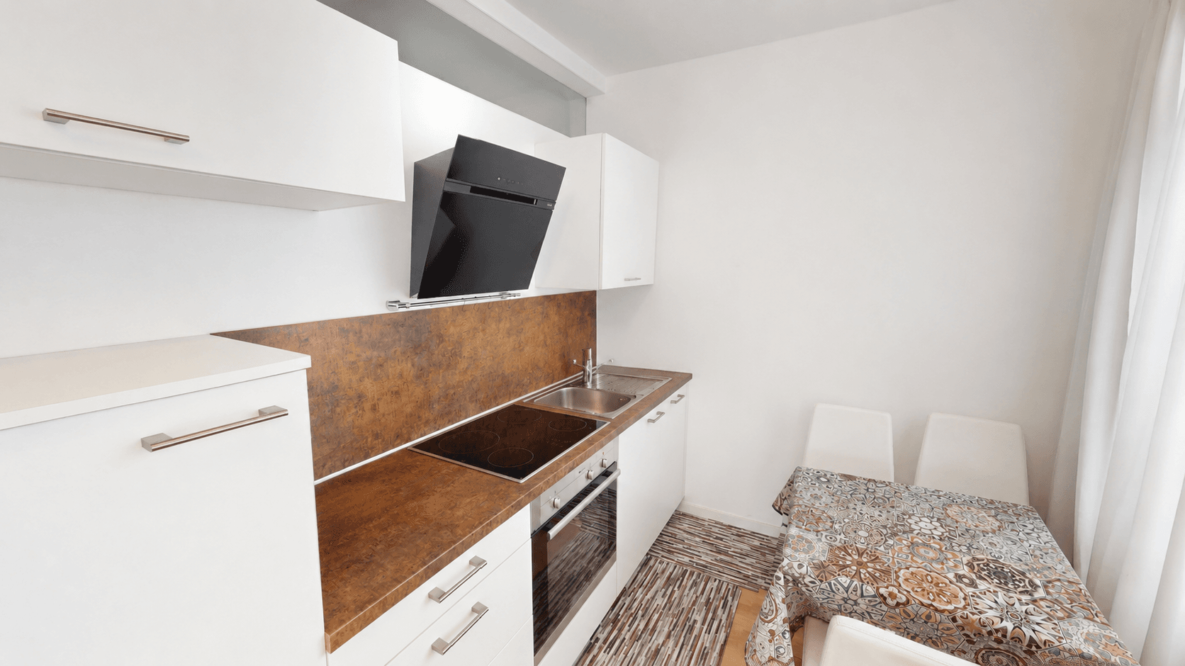 Moderne Einbauküche mit weißen Fronten, Induktionskochfeld, Backofen und Spüle.
