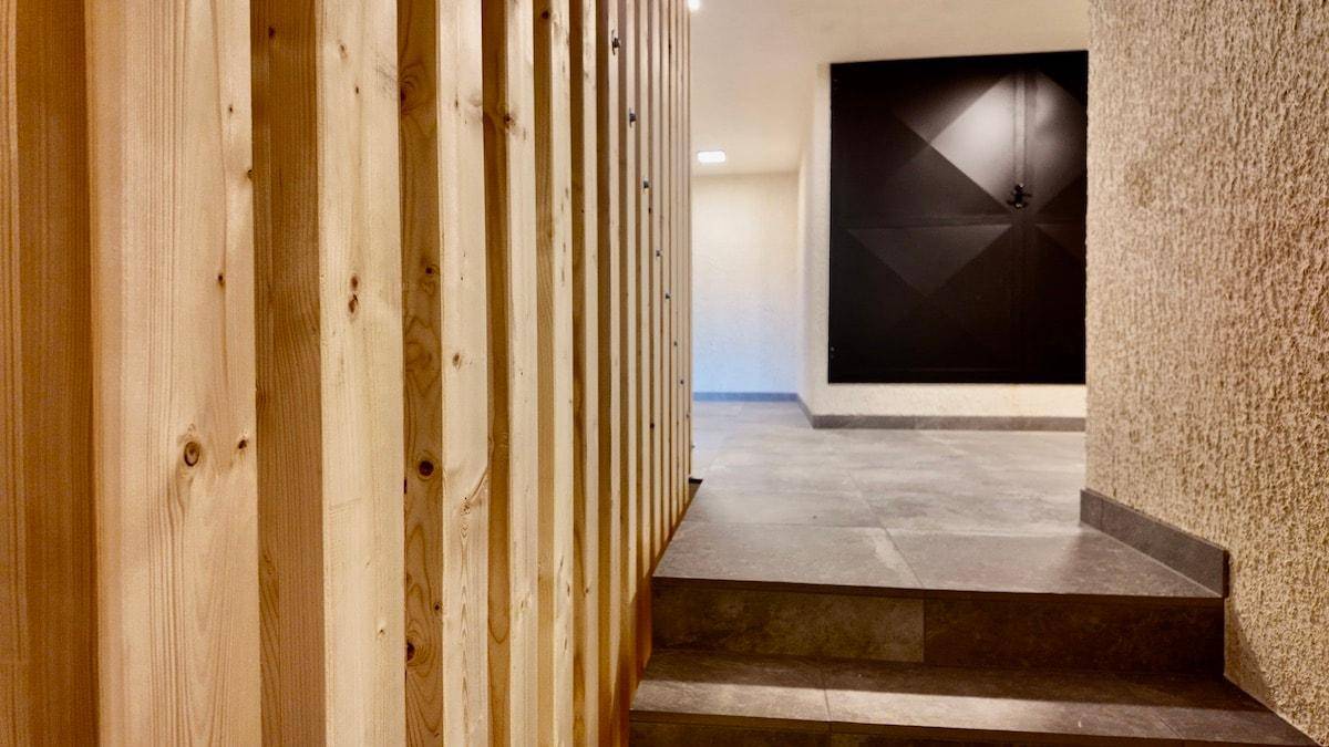 Moderner Flur mit Holzverkleidung und Steinfliesenboden, der zu einem weiteren Bereich führt.