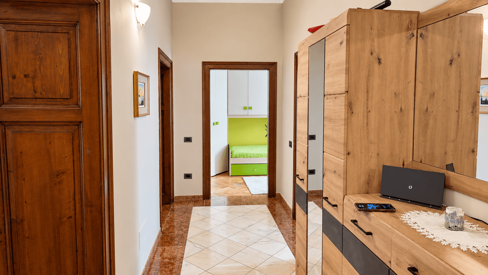 Flur mit Holztüren, Fliesenboden und einem Blick in angrenzende Zimmer.