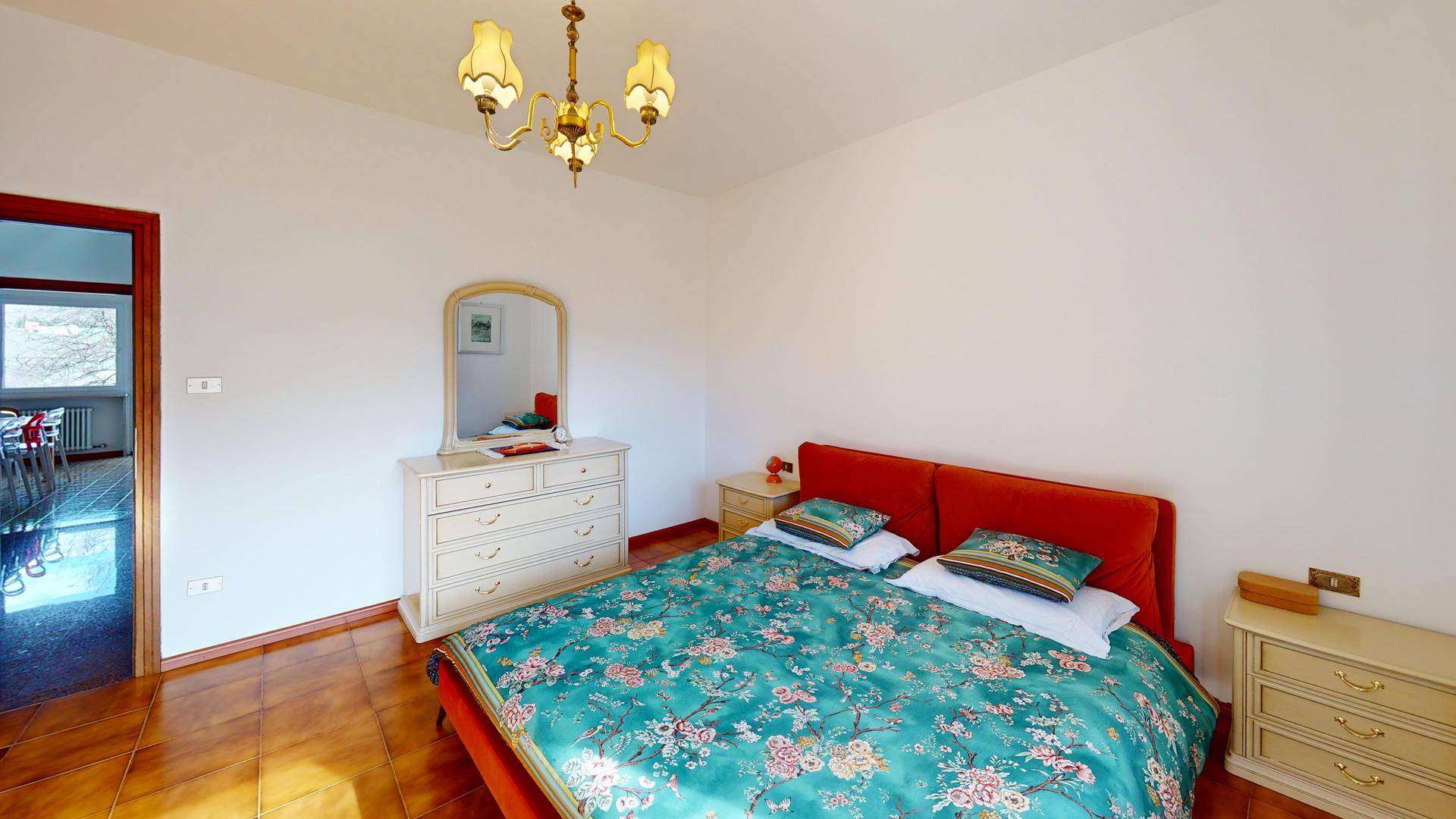 Schlafzimmer mit Doppelbett, Kommode und Fliesenboden.