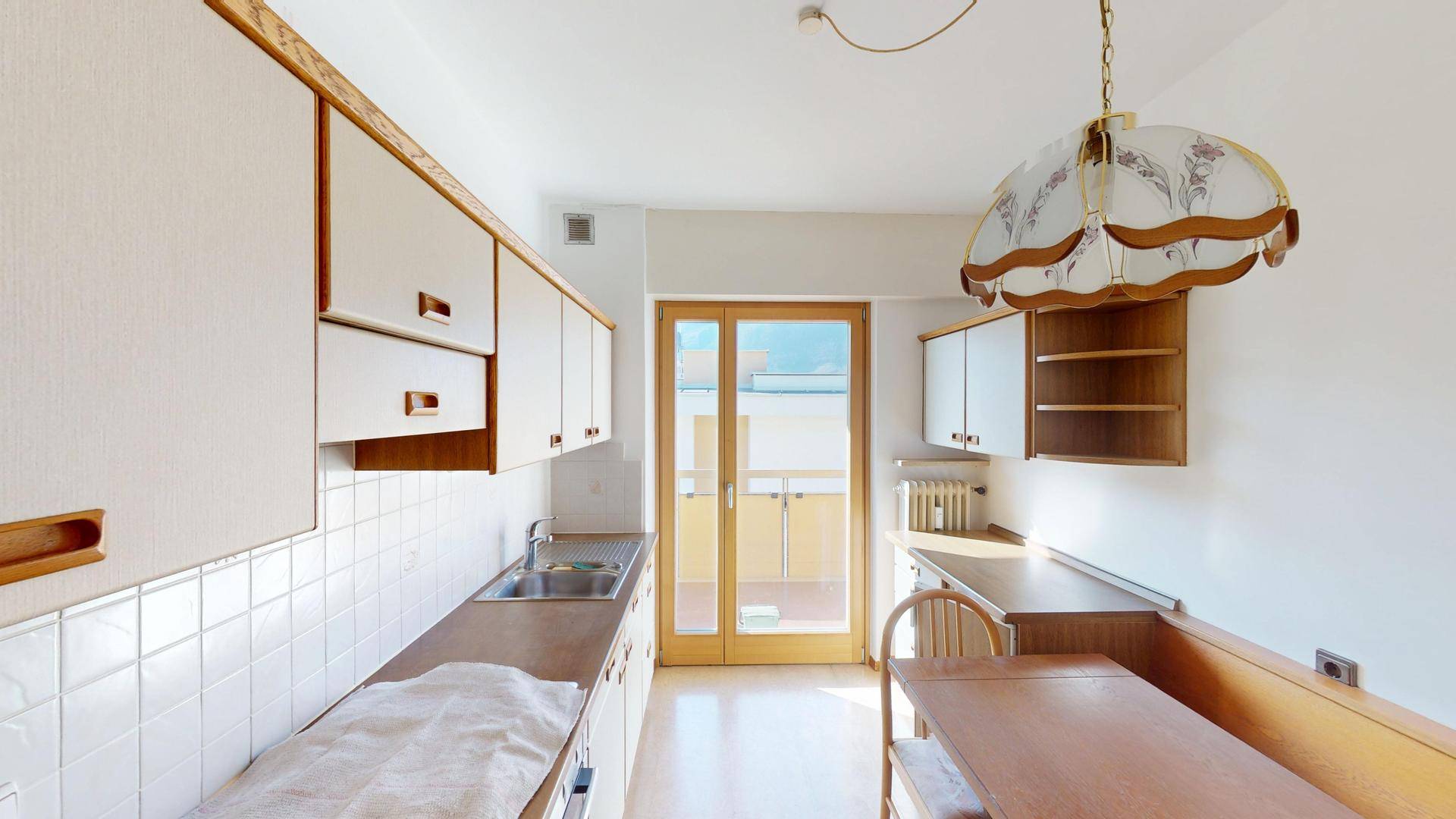Traditionelle Küche mit Essbereich, weißen Schränken und Zugang zum Balkon.