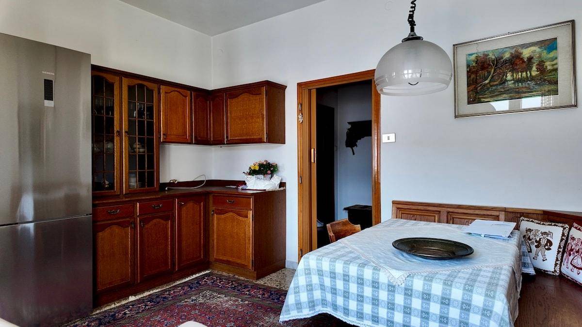 Küche mit traditionellen Holzschränken, Esstisch und einem modernen Kühlschrank.