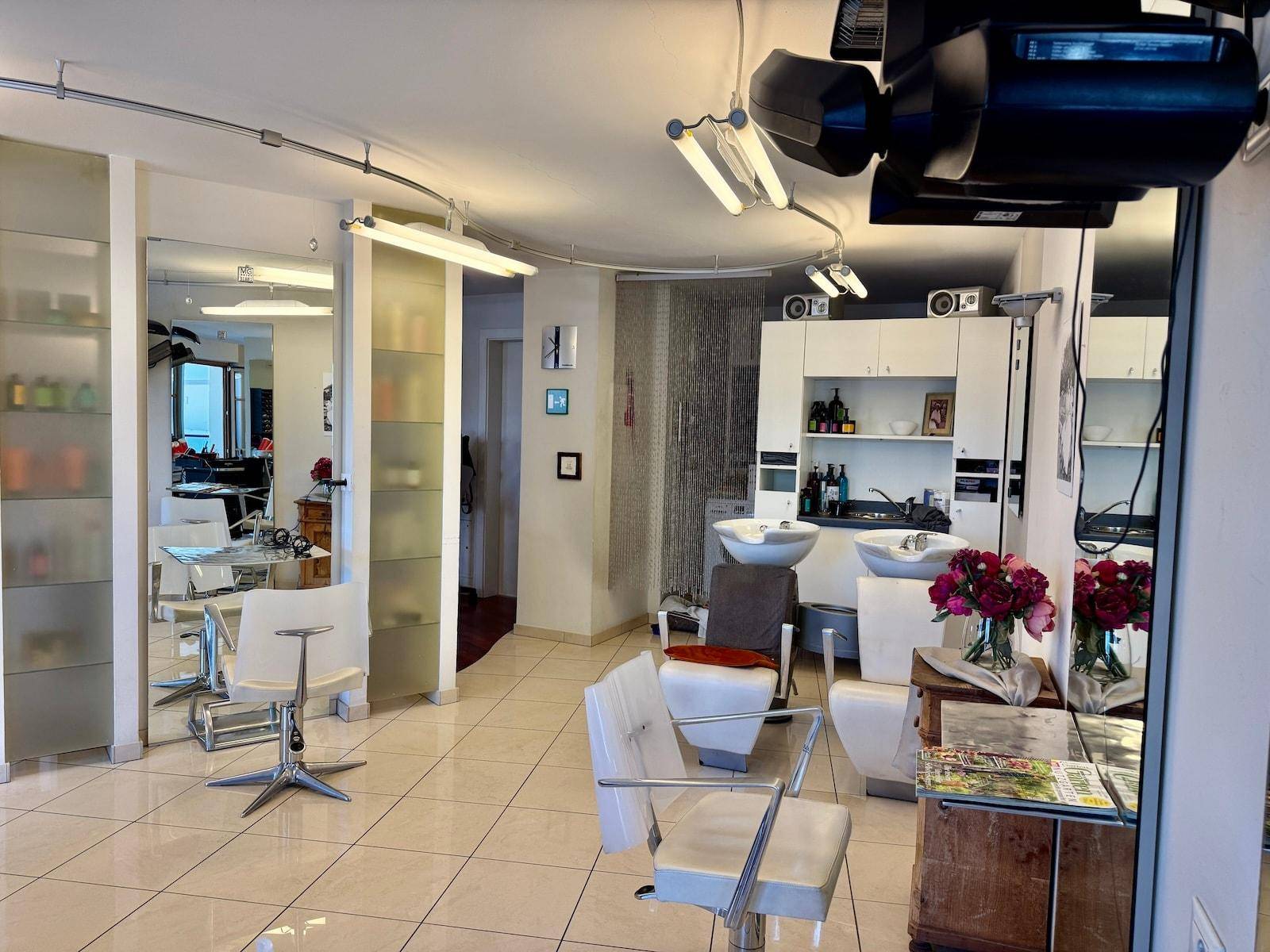 Überblick über den Friseursalon mit Arbeitsplätzen, Waschbecken und großen Spiegeln.
