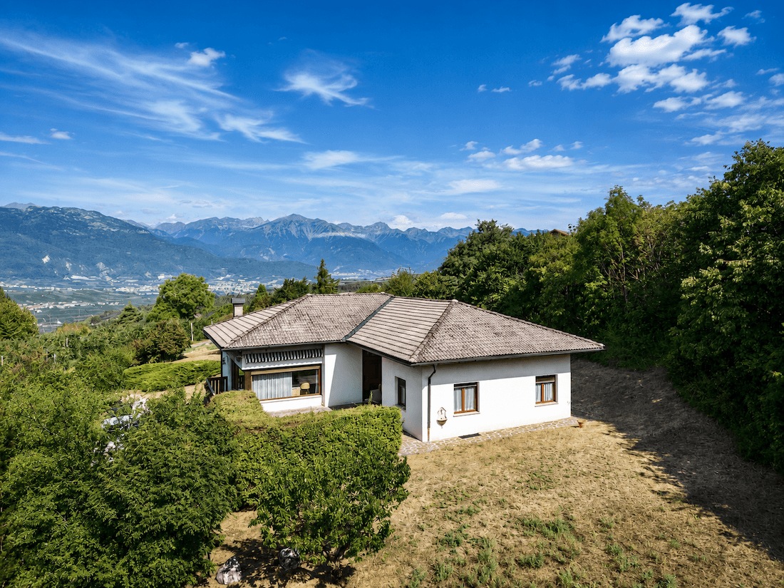 Haus in Hanglage mit Panoramablick auf die Berge und das Tal.