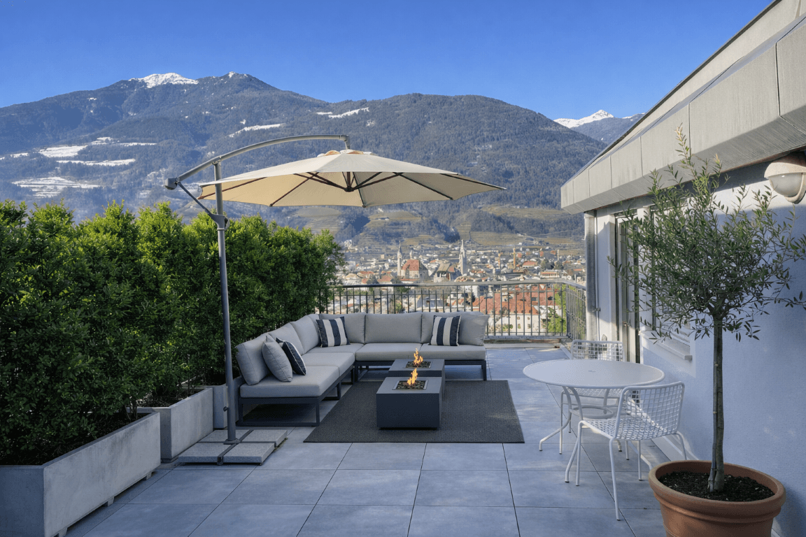 Großzügige Dachterrasse mit Lounge-Möbeln, Feuerstelle und Panoramablick auf die Stadt und Berge.