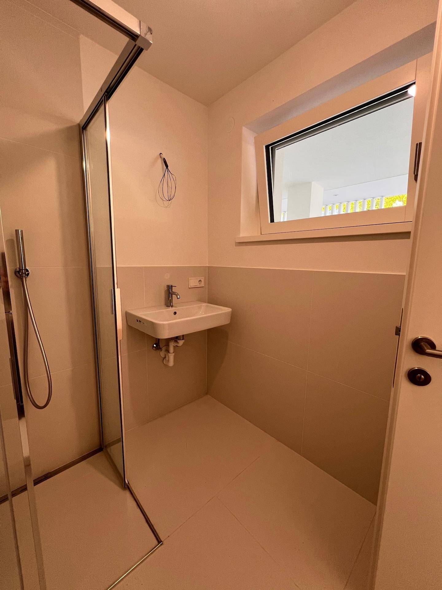 Modernes Badezimmer mit Duschkabine, Einzelwaschbecken und einem Fenster für Tageslicht.